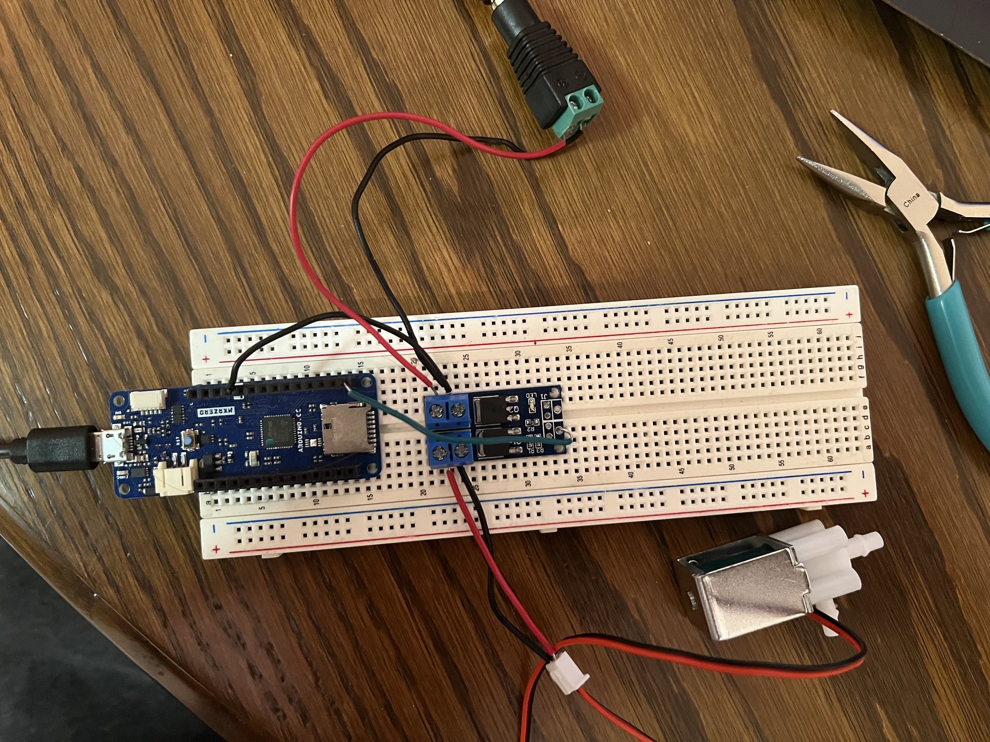 An Arduino MKR Zero and a MOSFET module on a breadboard, wired to a small solenoid valve