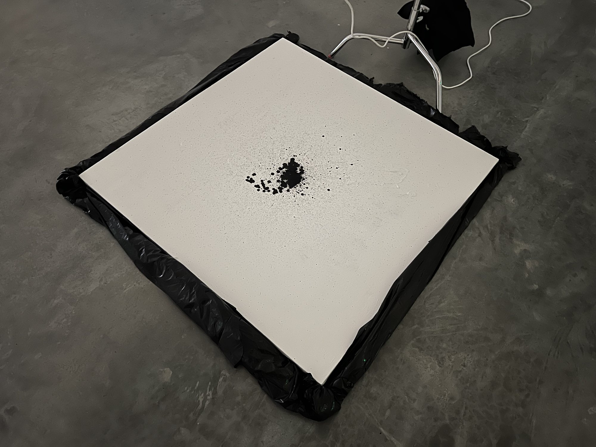 The canvas on the floor during the installation, with a cluster of ink at its center