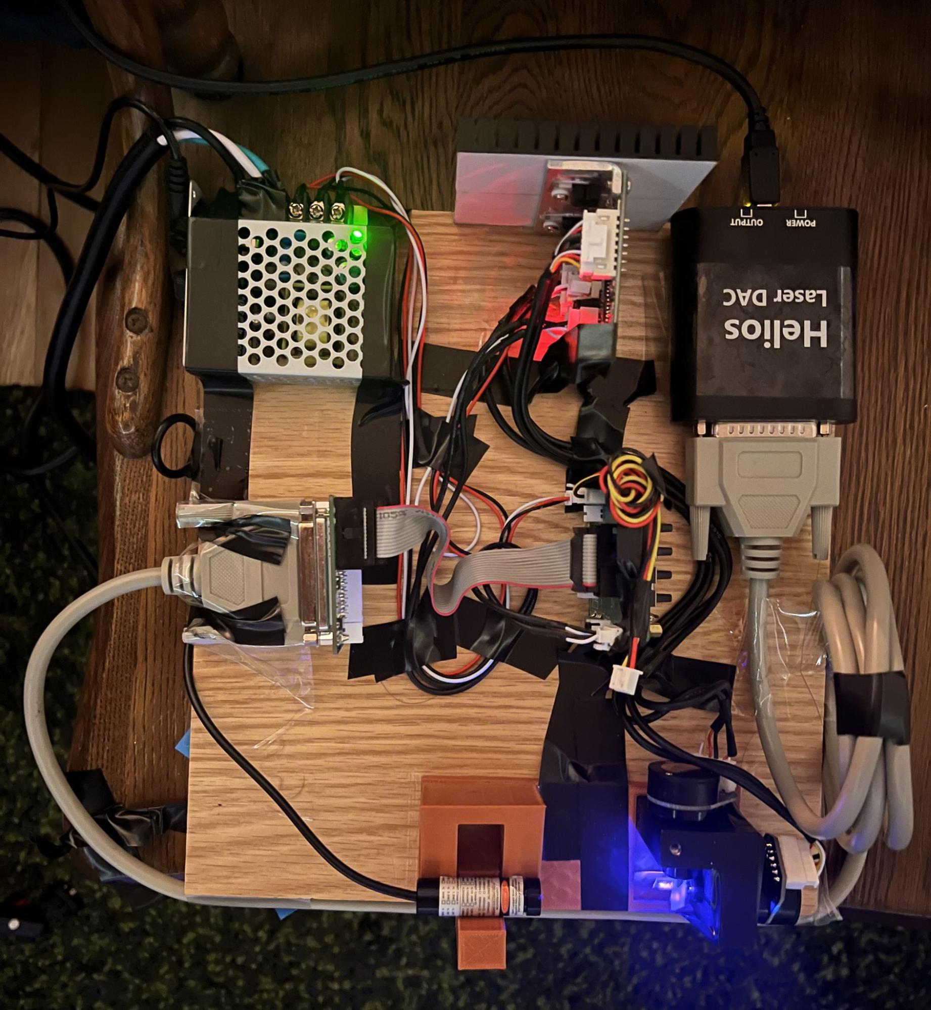 All of the galvo components mounted on a wooden board: power supply, driver, heatsink, Helios DAC, galvo head, and the laser in its printed mount