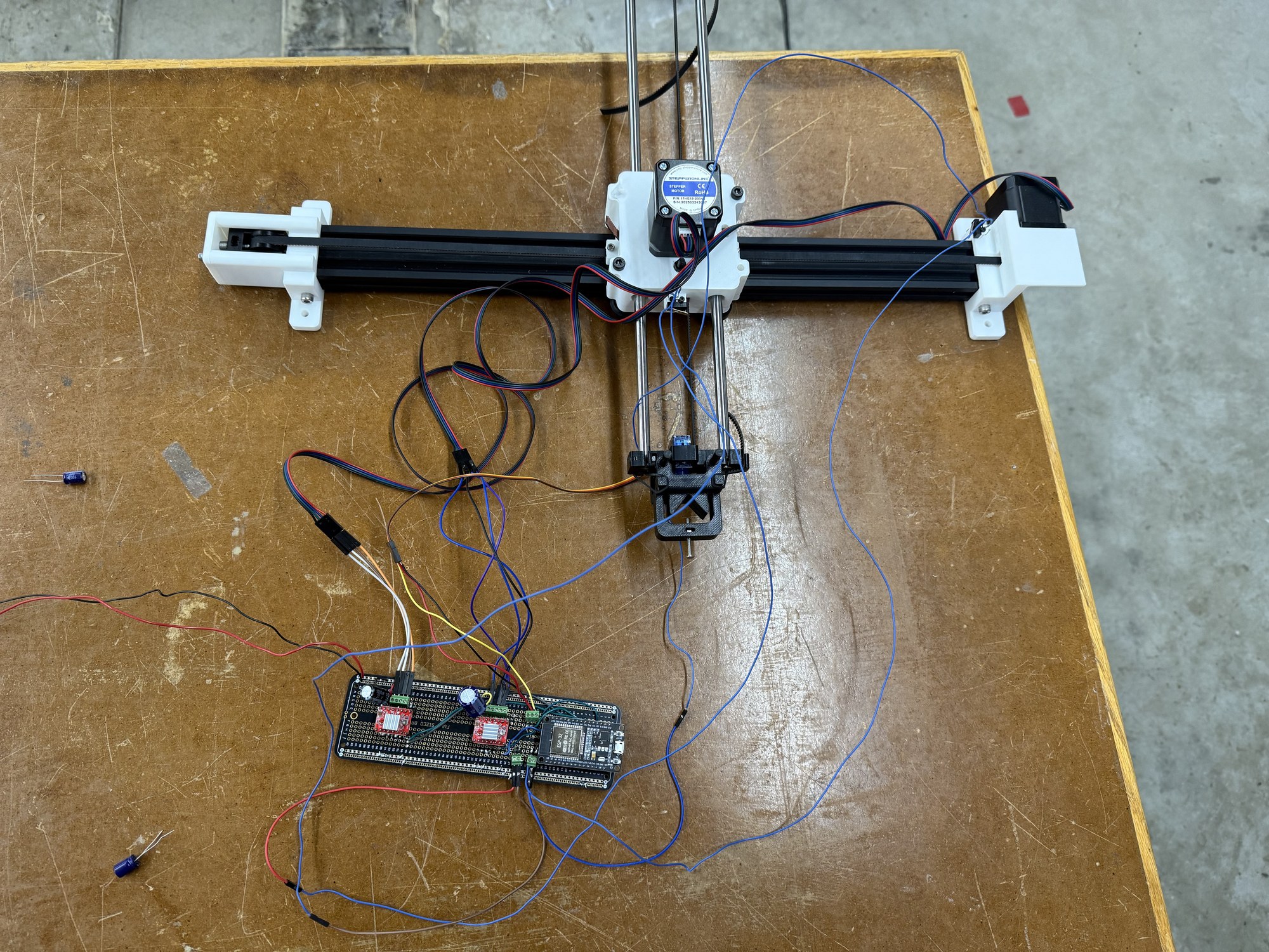 The plotter lying flat on its chipboard base, wired to a soldered circuit board