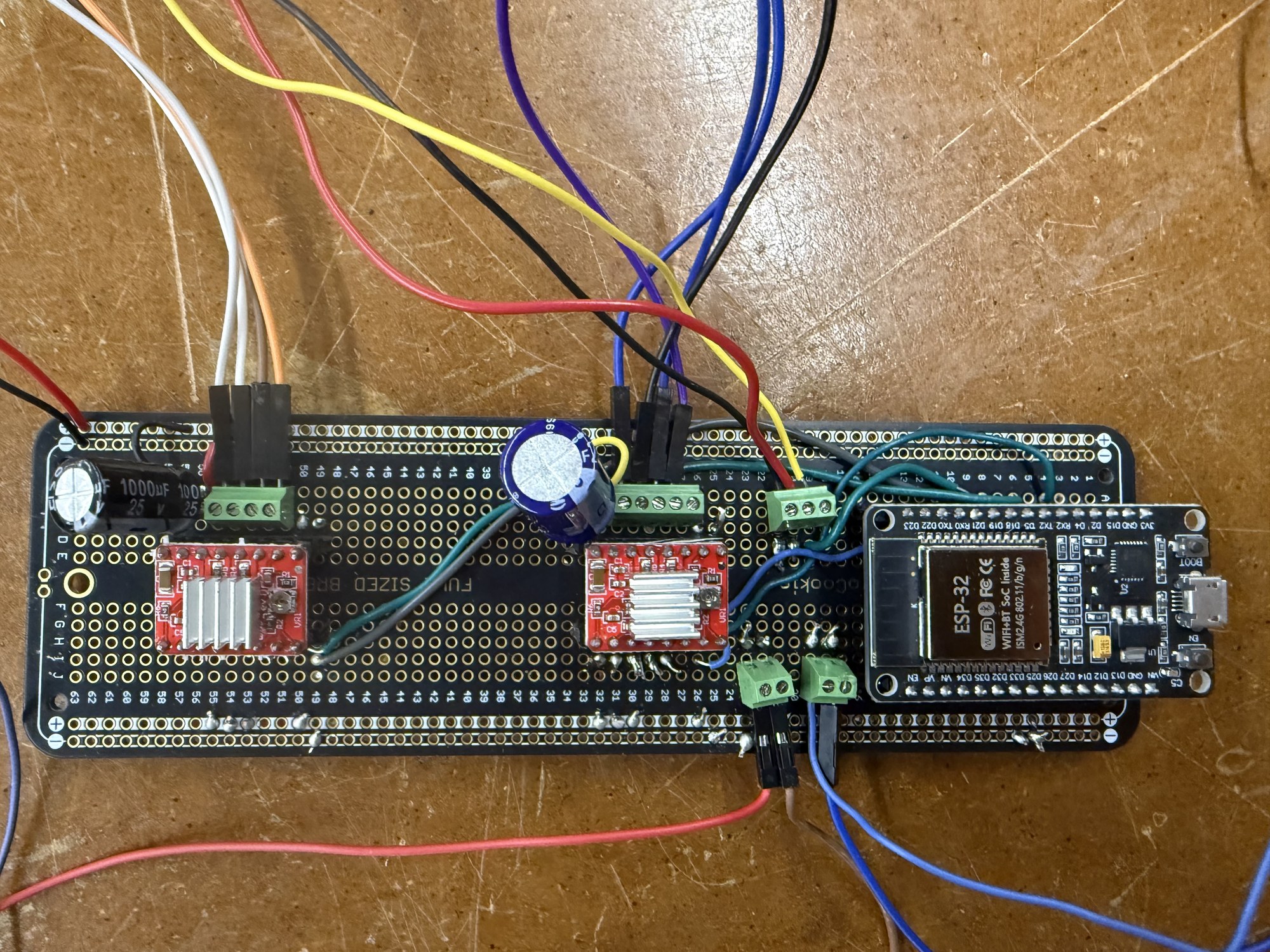 The soldered circuit board with an ESP32 DevKit, two stepper drivers, and capacitors